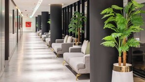 Un hall d’hôtel avec un long couloir bordé de canapés et de plantes en pot.
