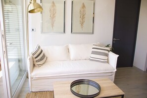 Relax in this stylish living room with a sofa, coffee table, and artwork, leading to an outdoor area.