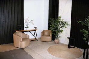 Relax in this serene space, featuring two comfortable armchairs, a coffee table, and a lush greenery corner.