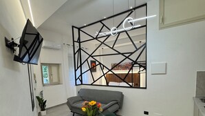 A modern living room with a round table, green chairs, a sofa, and a decorative wall piece. - La Dimora del Centro - Agrigento Complete apartment in the heart of the City (Agrigento)
