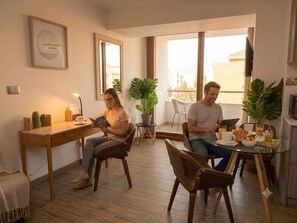 Ein modernes Wohnzimmer mit Holztisch, Stühlen, Couchtisch und Blumentöpfen.
