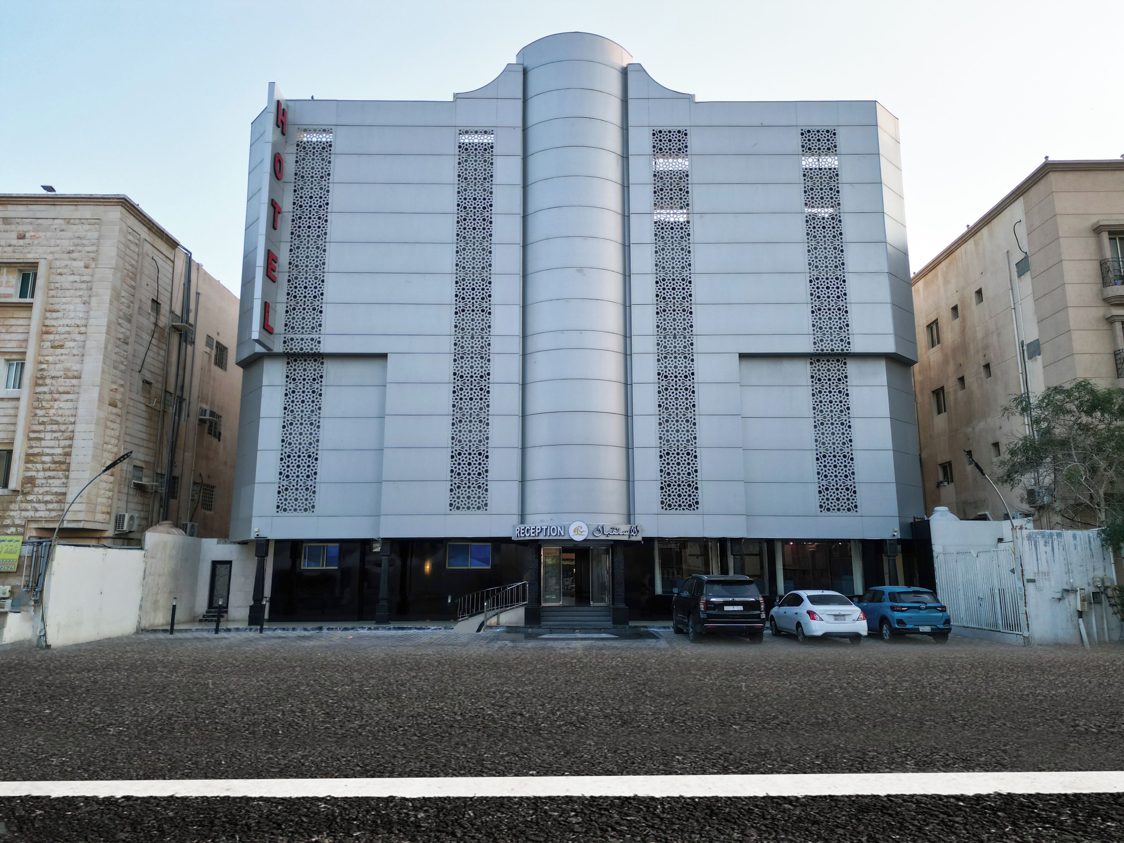 A modern building with a reception area and multiple cars parked in front.