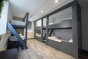 Ein modernes, kompaktes Zimmer mit Etagenbetten, einer Treppe und Blick durch ein Fenster.