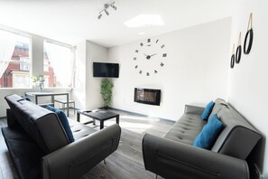 A modern living room with a sofa, a coffee table, and a TV mounted on the wall.