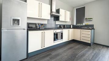 A modern kitchen with a built-in refrigerator, oven, microwave, and a stainless steel range hood.