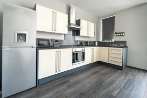 Eine moderne Küche mit einem eingebauten Kühlschrank, Backofen, einer Mikrowelle und einer Edelstahl-Dunstabzugshaube.