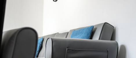 A modern living room with a gray sofa, a blue pillow, and three wall-mounted circular mirrors.