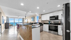 A modern kitchen with a central island, stainless steel appliances, and a view to the outside. - Majestic Beach Towers 2-801 (Panama City Beach)