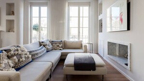 A modern living room with a sectional sofa, a small table, and a fireplace. - Spectacular 4 Bed House, Pimlico (London)