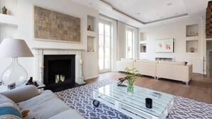 A spacious living room with a fireplace, a sofa, a coffee table, and a large abstract painting on the wall. - Spectacular 4 Bed House, Pimlico (London)
