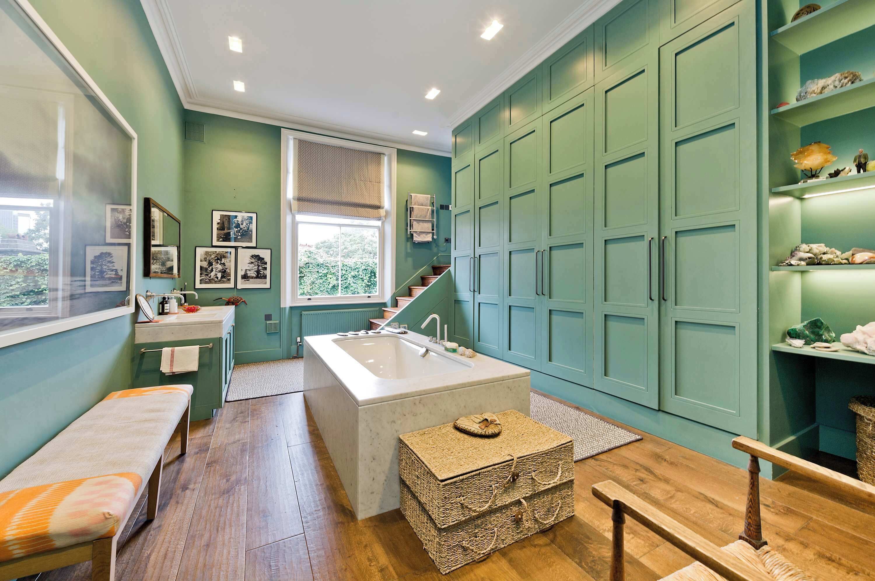 A bathroom with a freestanding bathtub, a bench, and a wicker basket.