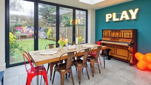 A dining area with a piano, a 'PLAY' sign, and a view of the garden. - 4 Bedroom House, Barnes (London)