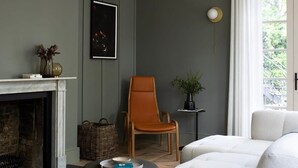 En moderne stue med pejs, en stor hvid sofa, en træstol og en hængende lampe.