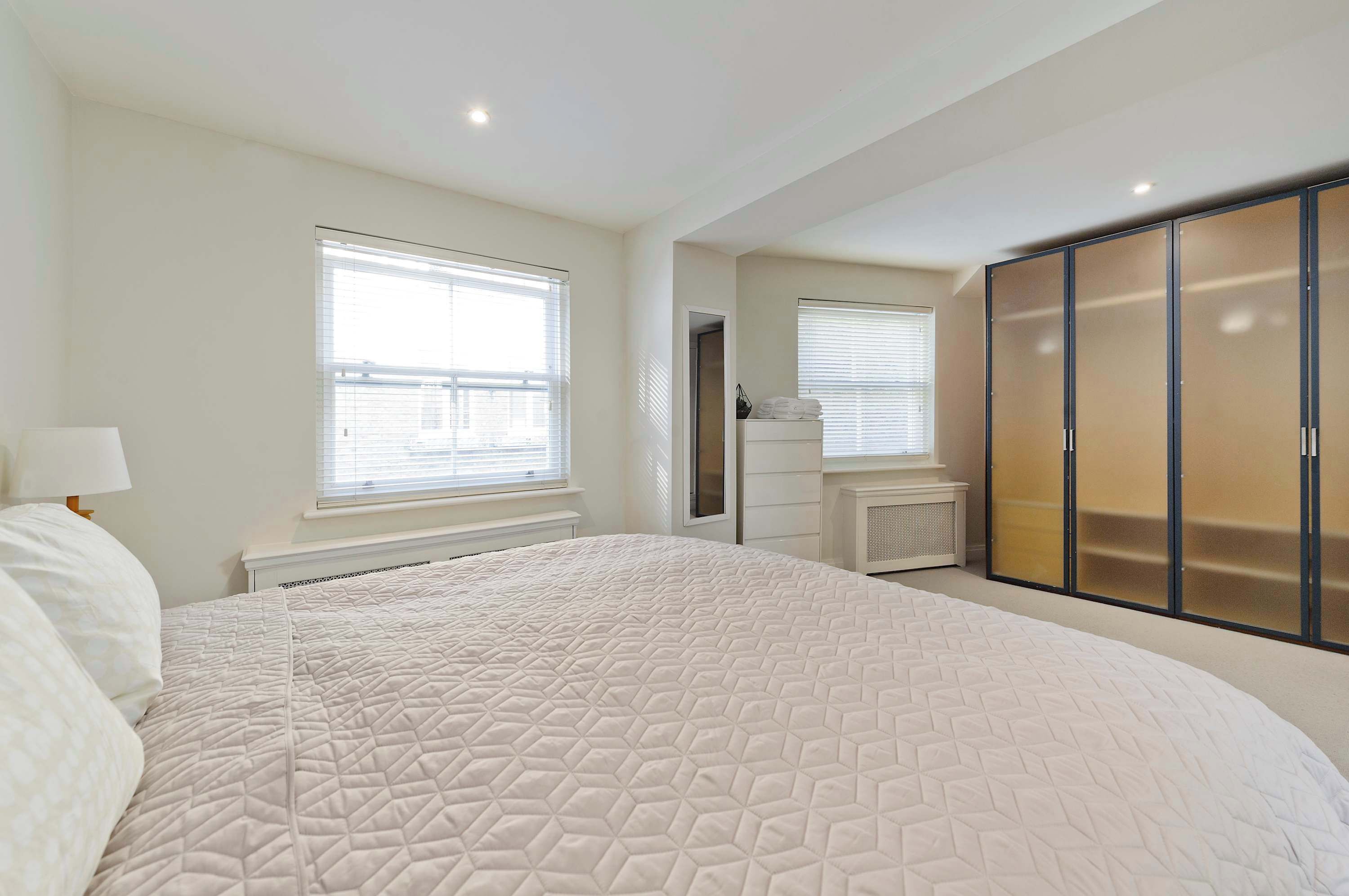 A bedroom with a large bed, a wardrobe, and a radiator.