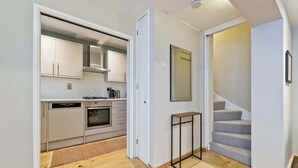 Una cocina compacta con electrodomésticos modernos, un pequeño comedor y una escalera que sube a otro nivel.