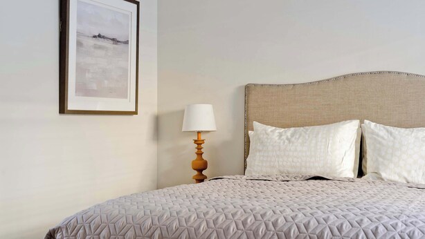 A neatly made bed with a quilted cover, a bedside lamp, and a framed picture on the wall. - 2 Bedroom Mews House, Marble Arch (London)