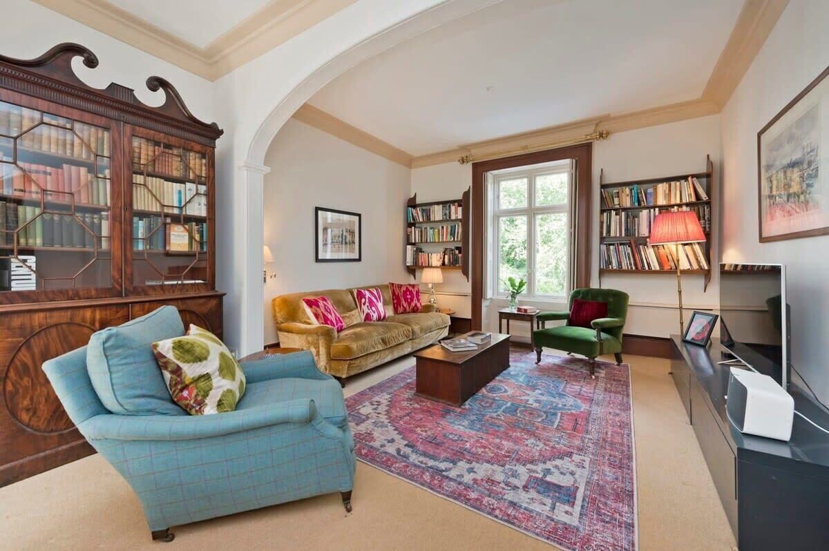 Ein Wohnzimmer mit einer Couch, einem Sessel, einem Couchtisch und einer großen Holzbibliothek.