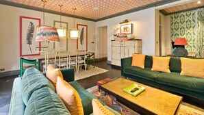 Een woonkamer met een groene bank, een salontafel en een eethoek met een witte tafel en stoelen.