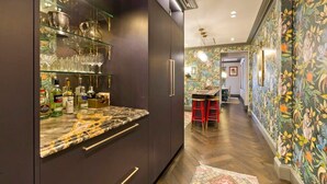 Een moderne keuken met een marmeren aanrecht, glazen planken en diverse keukengerei.