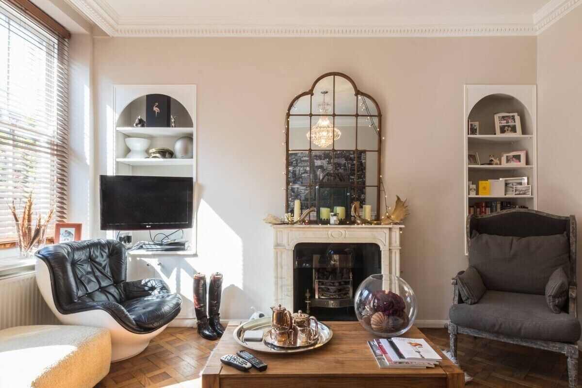 Una sala de estar con chimenea, televisor, un sillón de cuero negro, un sillón gris y una mesa de centro con una bandeja.
