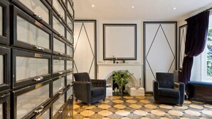 A room with a checkered floor, two armchairs, a fireplace, and a large black cabinet with glass doors. - Stylish 5 Bed House in St. John's Wood/maida Vale (London)