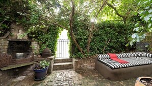 A garden area with a stone bench, a potted plant, and a black and white striped sofa. - Stylish 5 Bed House in St. John's Wood/maida Vale (London)