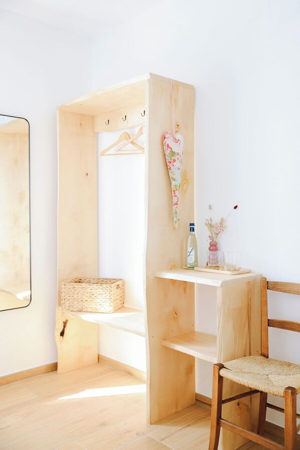 A room with a wooden wardrobe, a small table with a bottle and a vase, and a chair with a woven seat. - Bed & Breakfast alle Cantine (Salorino)