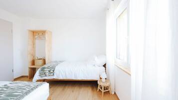 Ein Schlafzimmer mit einem Bett, einem Holzschrank, einem kleinen Tisch und einem Fenster mit Vorhängen.