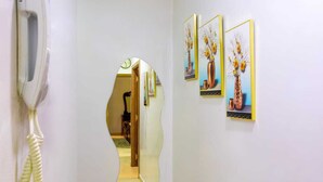 Un couloir avec un téléphone, une horloge et trois œuvres d’art encadrées accrochées au mur.