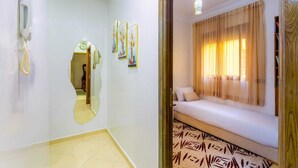 Une chambre d’hôtel avec un lit, une table de chevet, un miroir et un téléphone.