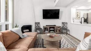 Un salon comprenant un canapé, deux fauteuils, une table basse, un téléviseur à écran plat et une cheminée.