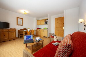 A compact living space with a dining area, a kitchenette, a television, and a red sofa. - Swimming pool, sauna, balcony, parking, tv, ski locker, 36m², Saint Sorlin d'Arves (Saint-Sorlin-d'Arves)