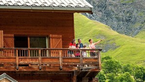 Une cabane en bois dotée d’un balcon donnant sur un paysage montagneux.