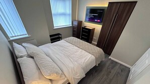 A bedroom with a bed, a TV mounted on the wall, and a wardrobe. - 2br-sleeps4-freeparking-wifi-smarttvs (Manchester)
