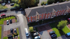 An aerial view of a residential building with multiple floors, a parking lot, and surrounding greenery. - 2br-sleeps4-freeparking-wifi-smarttvs (Manchester)