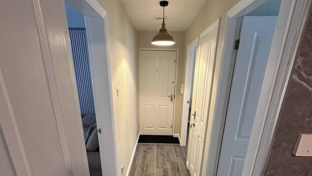 A hallway with wooden flooring, white doors, and a ceiling light fixture. - 2br-sleeps4-freeparking-wifi-smarttvs (Manchester)