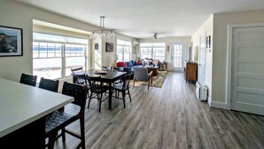A spacious living area with a dining table, chairs, a sofa, and a TV. - Beachfront House w/Fire Pits & Ocean Views, (Ellsworth)