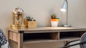 A wooden desk with a globe, a plant, and a desk lamp. - The Grande 1BD 1BA - Full Kitchen Guest Suite (Calgary)