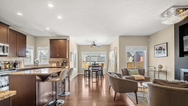 A spacious kitchen with a central island, a dining area with a table and chairs, and a living room with a sofa and armchairs. - The Venti - 3BD 2BA Yard Garage & Upper Suite (Calgary)