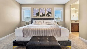 A bedroom with a large bed, a bench, and artwork on the wall. - The Venti - 3BD 2BA Yard Garage & Upper Suite (Calgary)