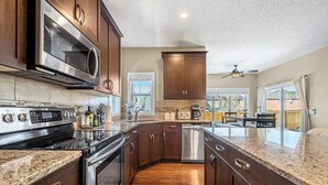 A modern kitchen with dark wood cabinets, stainless steel appliances, and a granite countertop. - The Venti - 3BD 2BA Yard Garage & Upper Suite (Calgary)