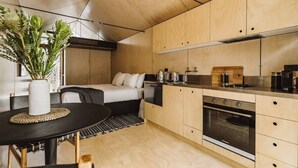 Una cocina compacta con muebles de madera, un horno y un comedor con mesa y sillas.