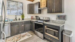 Une cuisine moderne avec des meubles de couleur sombre, des appareils électroménagers en acier inoxydable et un plafond en bois.