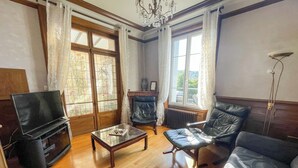 A living room with a TV, leather sofa, and a coffee table. - L'Arpège du Puy - House* ParkingView * Family* 10min walk from Center (Le Puy-en-Velay)