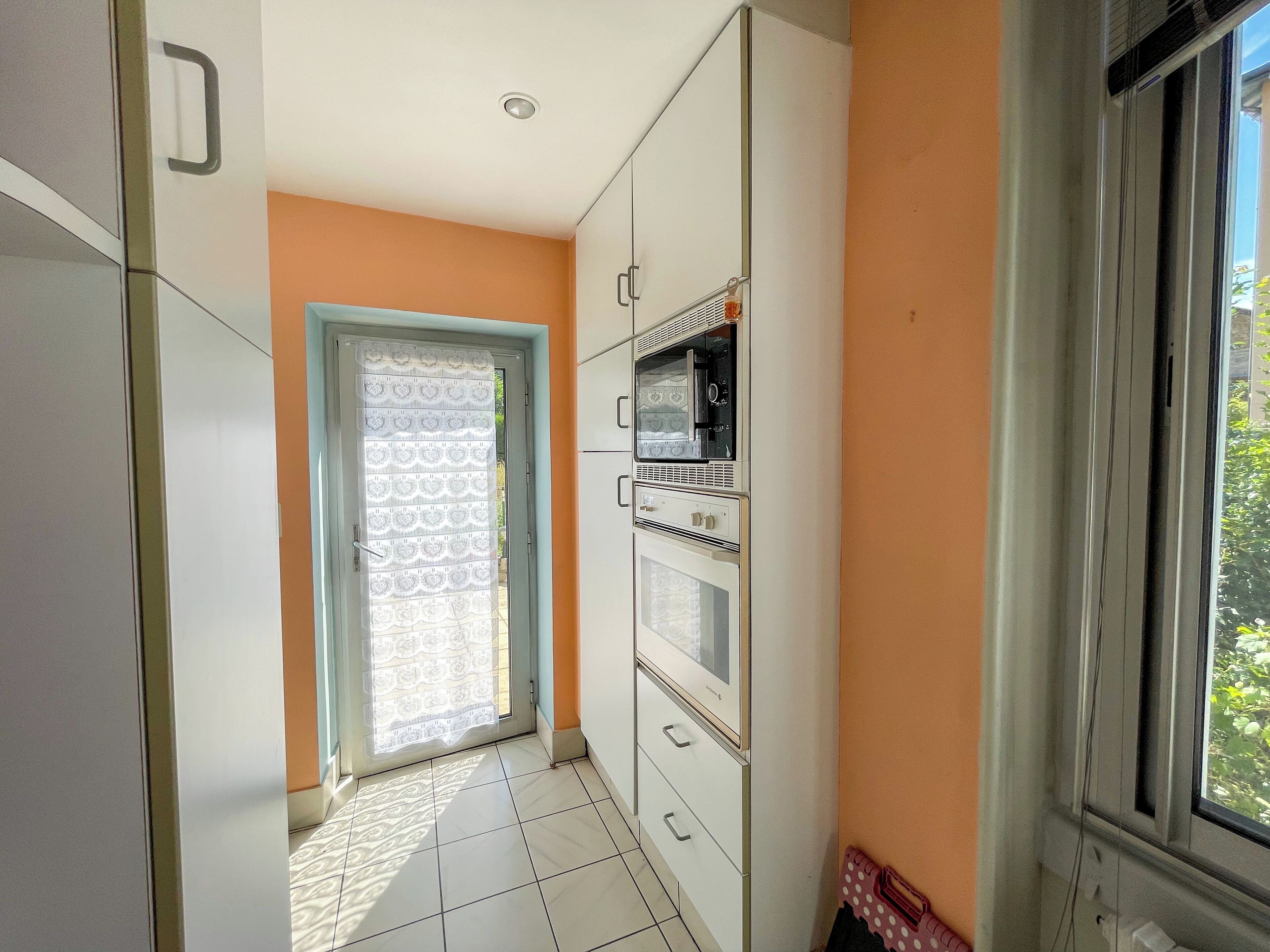 Una cocina con microondas, horno y ventana que da a zonas verdes.