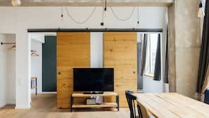 Un salon moderne avec un meuble TV en bois, une table à manger et une grande fenêtre.