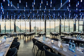 Ein Restaurant mit gedeckten Tischen, Blick auf die Stadt und hängenden Lampen.