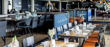 A restaurant with tables set for dining, hanging light fixtures, and a counter area.