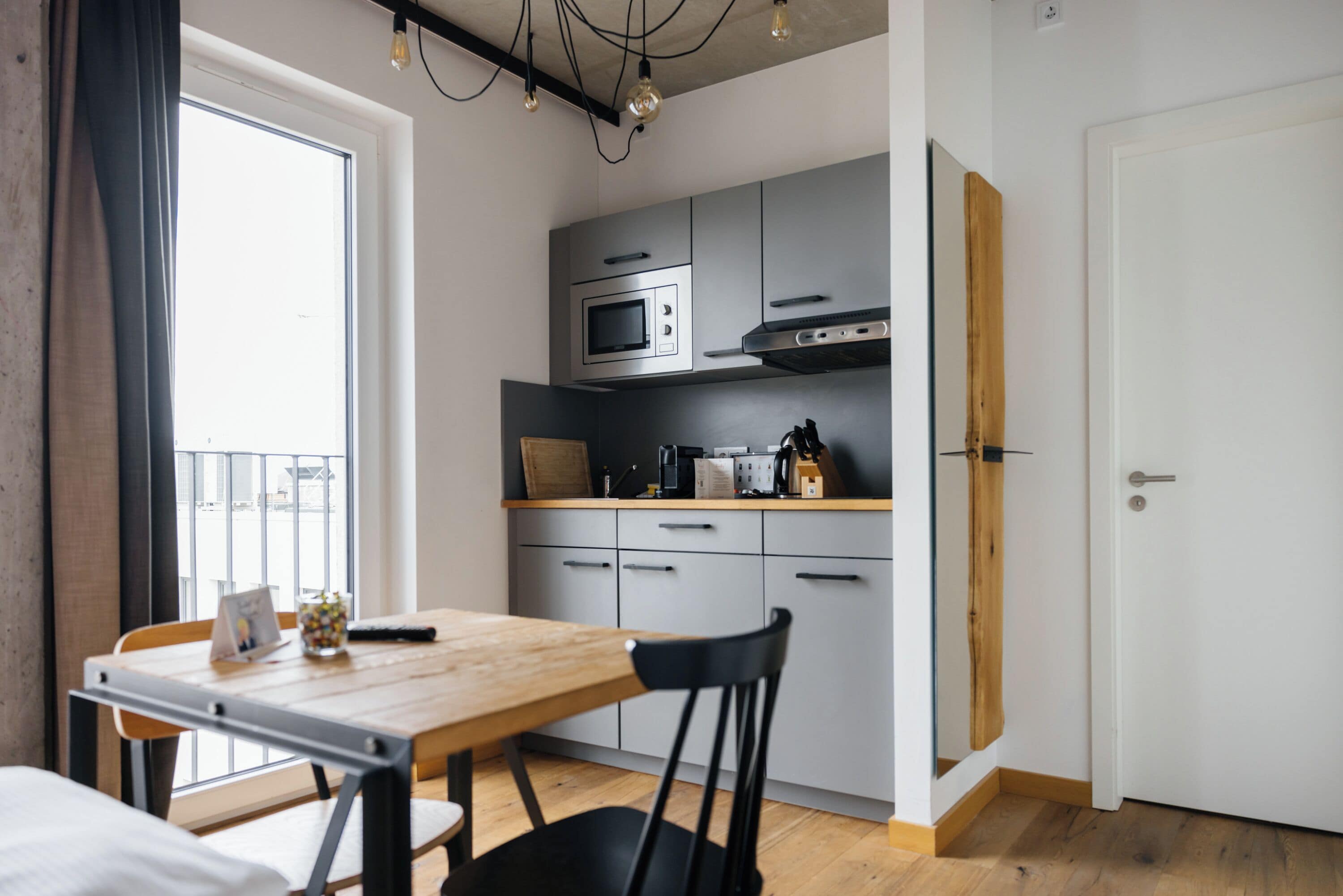 Une cuisine compacte dotée d’appareils électroménagers modernes, une table à manger avec des chaises et une vue par la fenêtre.