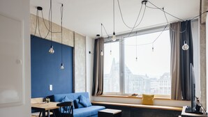 Un espace de vie moderne avec un mur bleu, une table en bois, un canapé et une fenêtre donnant sur la ville.